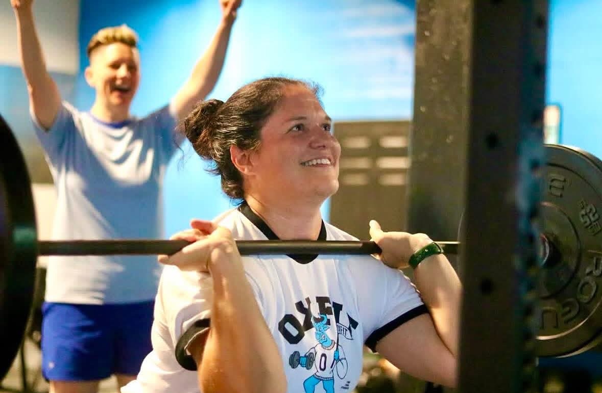 An OxFit member lifting while a teammate cheers